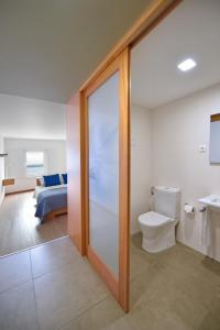 a bathroom with a toilet and a bedroom at Casa da Baía - Guest House in Horta