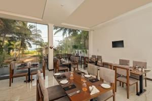 a restaurant with wooden tables and chairs and a large window at Beverly Beach Negombo in Negombo