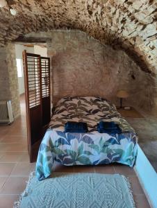 a bedroom with a bed in a stone wall at Le Relais Provençal in Barret-de-Lioure