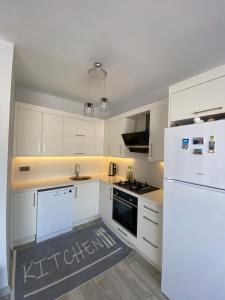 a kitchen with white cabinets and a white refrigerator at Marina Guest House in Çeşme