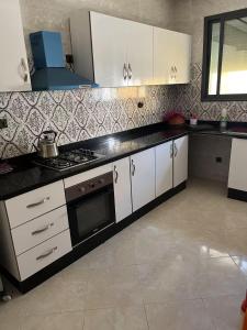 a kitchen with white cabinets and a stove top oven at Bouznika mandarona in Bouznika