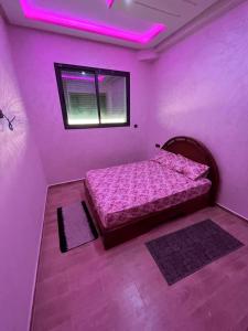 a bedroom with a bed and a window with purple lights at Bouznika mandarona in Bouznika