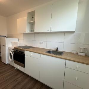 a kitchen with white cabinets and a sink and a refrigerator at WDI - Workers Apartments in Herten +7 photos
