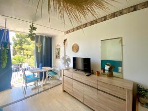a living room with a television and a dining room table at Échappée Bohème & Lumière in La Grande-Motte