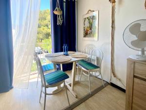 a dining room with a table and chairs and a window at Échappée Bohème & Lumière in La Grande-Motte