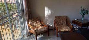 two chairs and a table in a room with a window at Olive rest in Wesselsbron
