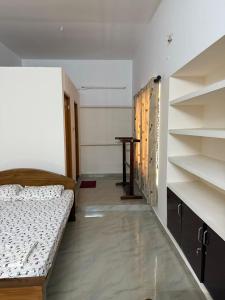 a room with a bed and a table and shelves at Bindas in Trivandrum