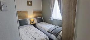 two beds in a small room with a mirror at Big Boss Caravan-Camber Sands,Sleep 8, Free Wi-Fi, Netflix, Parking in Camber