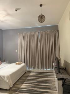 a bedroom with a bed and a television and curtains at One Click in Dubai