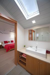 a bathroom with a sink and a bedroom with a bed at Casa da Baía - Guest House in Horta