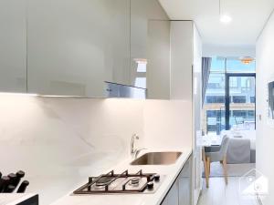 Una cocina blanca con fregadero y estufa. en Serenity Studio with Balcony at Azizi Riviera, en Dubái