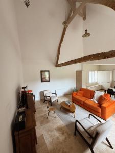 ein Wohnzimmer mit einem orangenen Sofa und Stühlen in der Unterkunft Gîte Le Guet du Roy in Boismont