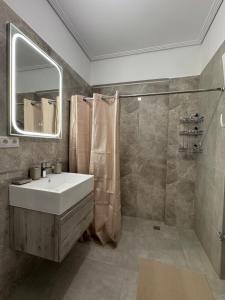 a bathroom with a sink and a shower and a mirror at GuccisCozyStudio in Artemida