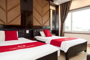 a bedroom with two beds with red and white sheets at CHIEN CONG Hotel in Ha Long