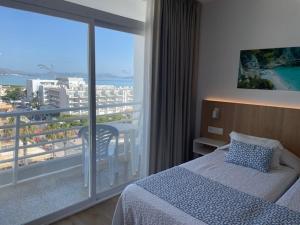 una camera da letto con un letto e un balcone con vista di Hotel Sultán a Can Picafort