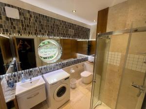 a bathroom with a sink and a washing machine at 3 x Studios Golden Manor in Hanwell