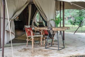 a table and chairs in front of a tent at Dolly Farm & River Camp, Luxury Tents in Usa River +44 photos