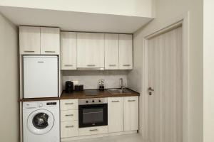 a kitchen with white cabinets and a washer and dryer at Studio Lumo in Nea Moudania +5 photos