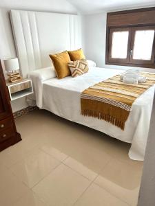 a white bedroom with a large bed with pillows at CENTER APARTMENT Mazagón in Mazagón