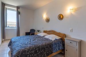 a bedroom with a bed with a blue comforter and a window at Micocoulier de la Maréchale in Orgnac-lʼAven