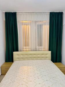 een slaapkamer met een bed en groene gordijnen bij City Rest Apartment in Oradea