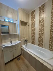 een badkamer met een wit bad en een wastafel bij City Rest Apartment in Oradea