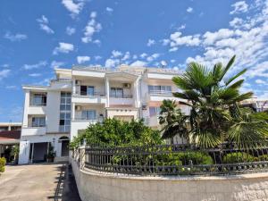a white building with a palm tree in front of it at Apartments Yll in Ulcinj