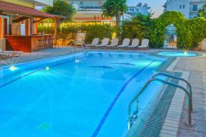 a large blue swimming pool with chairs in a hotel at Pavlos Hotel in Kos