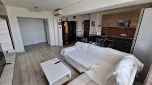 a living room with a white couch and a kitchen at MMT SweetHome Sud in Ploieşti