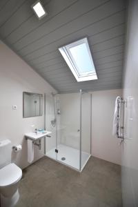 a bathroom with a shower and a toilet and a skylight at Casa da Baía - Guest House in Horta