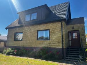 a yellow brick house with a black roof at Villa på Österlen in Borrby