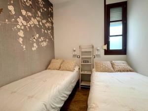 two beds in a small room with a window at inncadiz El Refugio de Gadir in Cádiz
