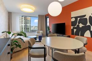 un salon avec une table, des chaises et une télévision dans l'établissement SkyPark Apartment with City Views Free Parking, à Nivy