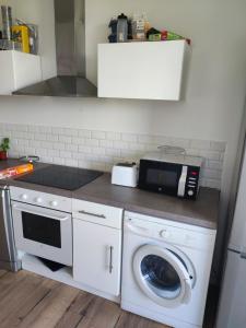 eine Küche mit Waschmaschine und Mikrowelle in der Unterkunft Appartement spacieux et lumineux, idéalement situé in Pessac