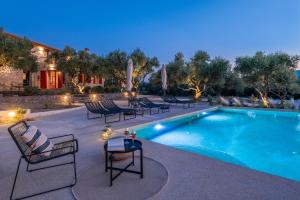 a swimming pool with chairs and a table next to it at Geracasa Stone Villa in Méson Yerakaríon