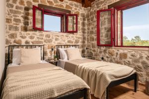 two beds in a room with two windows at Geracasa Stone Villa in Méson Yerakaríon +41 photos