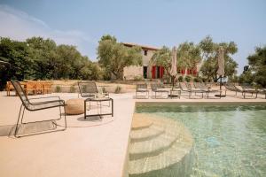 a group of chairs sitting around a swimming pool at Geracasa Stone Villa in Méson Yerakaríon