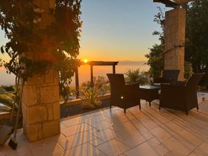 a patio with a table and chairs and the sunset at Villa Niloamna in Kritou Terra