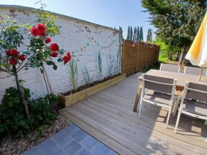 a wooden deck with a table and chairs and red roses at Le halage, charmante maison en bordure de rivière  +15 photos