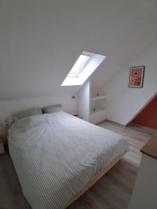a white bedroom with a bed with a skylight at Le halage, charmante maison en bordure de rivière 