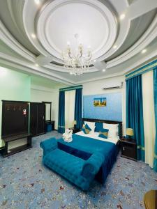 a large bedroom with a blue bed and a chandelier at Garden Boutique Hotel in Bukhara