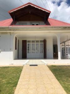a large white house with a red roof at Vivalavida Duplex in Les Abymes