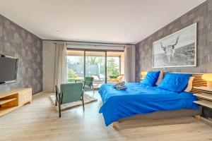 a bedroom with a blue bed and a flat screen tv at Le Loft, Spacieux 170 m2, Billiards, jardin, 3 chambres in Quimper