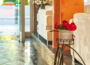 a vase filled with red flowers sitting on a table at Pavlos Hotel in Kos Town