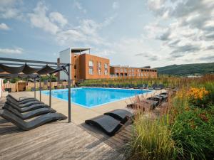 a swimming pool with lounge chairs next to a building at Hôtel & Spa Le Germain Charlevoix in Baie-Saint-Paul