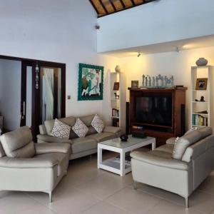 a living room with couches and a flat screen tv at Villa Casa Jamika in Seminyak