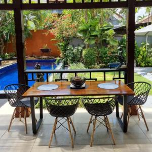 a wooden table and chairs on a patio with a pool at Villa Casa Jamika in Seminyak