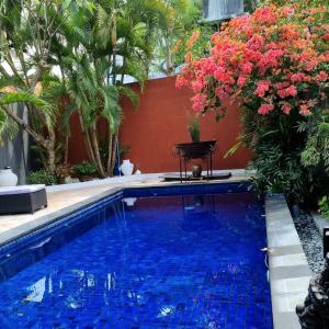 a swimming pool in a garden with flowers at Villa Casa Jamika in Seminyak