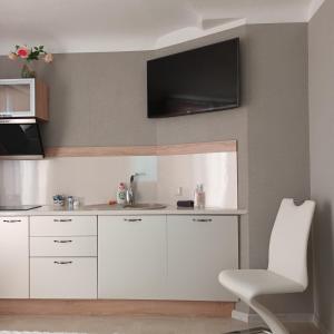 a kitchen with white cabinets and a tv on the wall at Baltā in Ventspils
