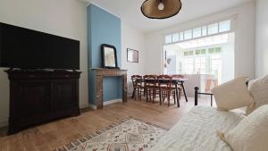 a living room with a television and a table with chairs at l'Eclat Malouin - Parking & Garden in Dunkerque